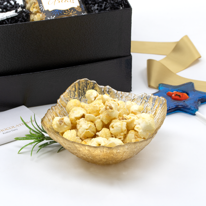 Gold and glass elegant snack bowl with artisan popcorn on a white surface with decorative elements