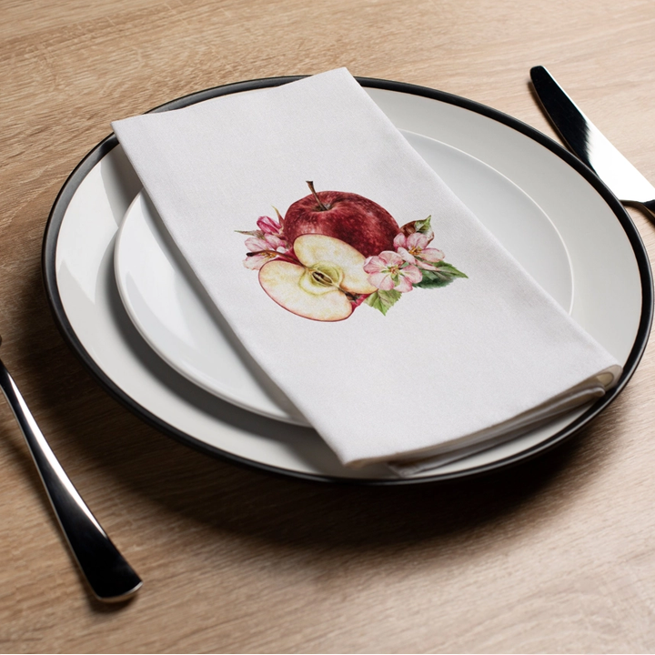 Napkin with apple design on a plate with cutlery on a wooden table