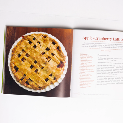 Apple Recipe Book open to a page with an apple cranberry lattice pie and recipe text.