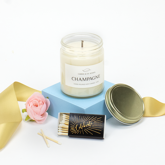 Champagne Scented Candle with Matchbox that says "Celebrate" gold embossed on cover.